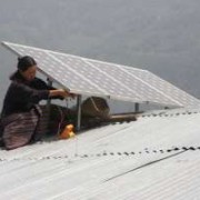 A woman installs a solar panels on the roof of her house in rural Bhutan